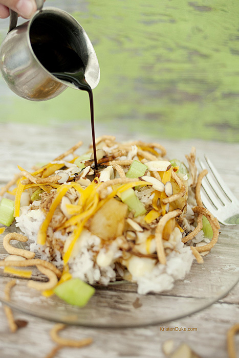 Hawaiian Haystacks recipe has a rice base, white sauce, cheese, pineapples, coconut, chow mein noodles, celery, almonds, cheese, and soy sauce. www.KristenDuke.com