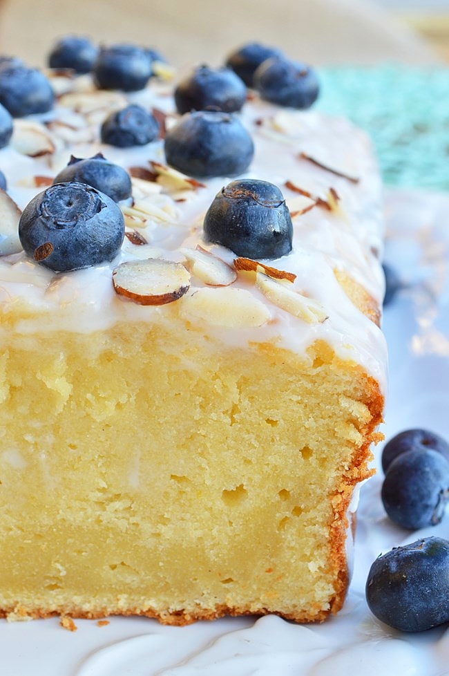 A perfectly moist and lemony Gluten Free Lemon Pound Cake with Vanilla Glaze topped with almonds and fresh blueberries. Does life get much sweeter???