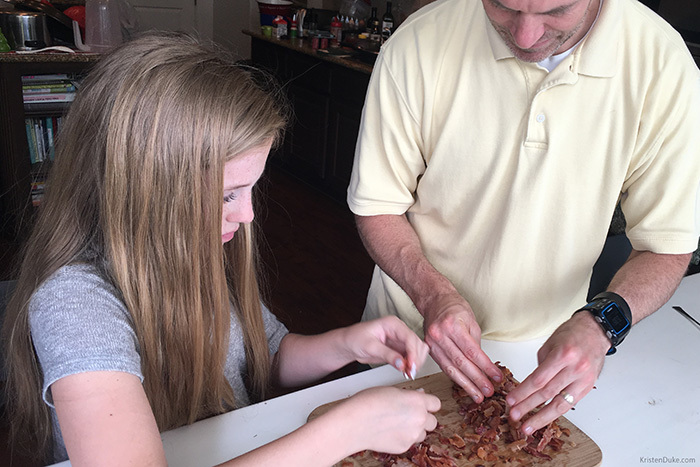 father and daughter crumbling bacon for spaghetti carbonara recipe